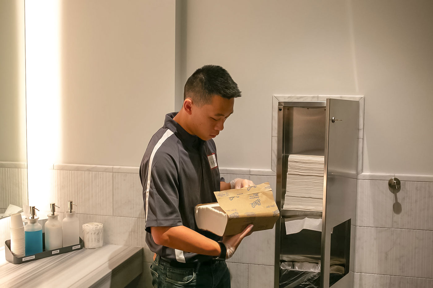 Janitor replacing paper towels in a restroom