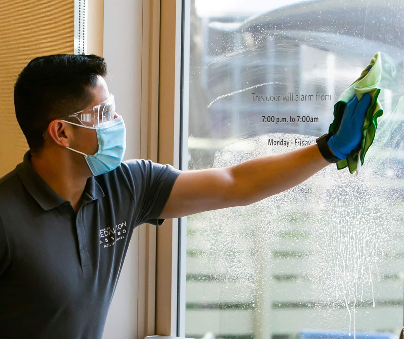 Janitor cleaning glass in an office lobby