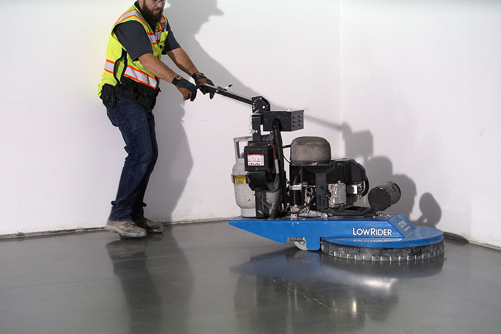Technician operating a commercial concrete polishing machine to restore and finish a hard surface floor
