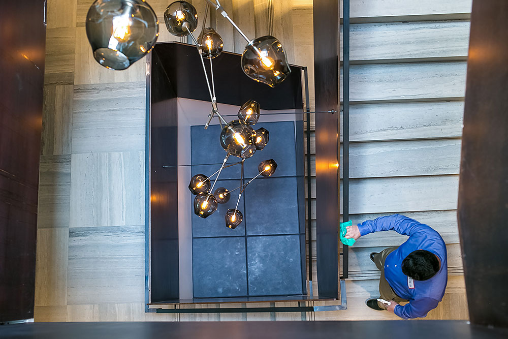 Janitor cleaning high touch surfaces in a modern workplace stairwell