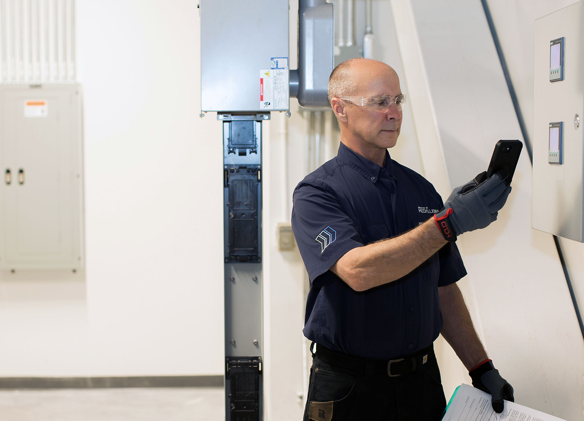 Facility technician reading a report on a mobile device in a riser room