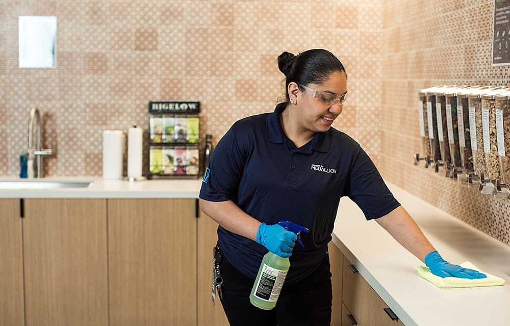 Day porter wiping down kitchen countertops in an office cafe