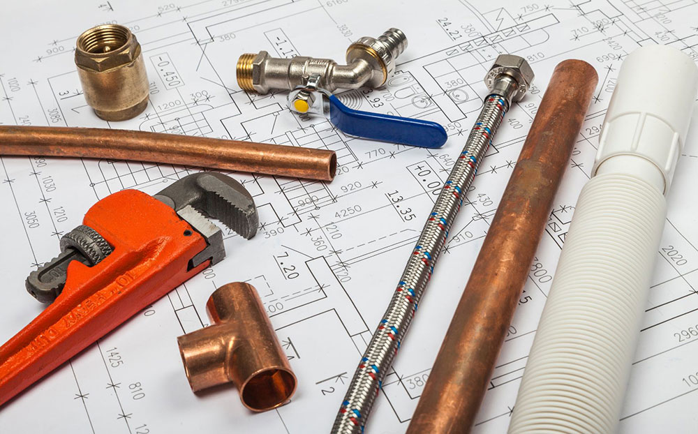 plumbing tools laid on a table with schematics over it