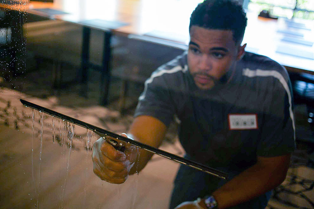 Day porter using a squeegee for commerical window cleaning