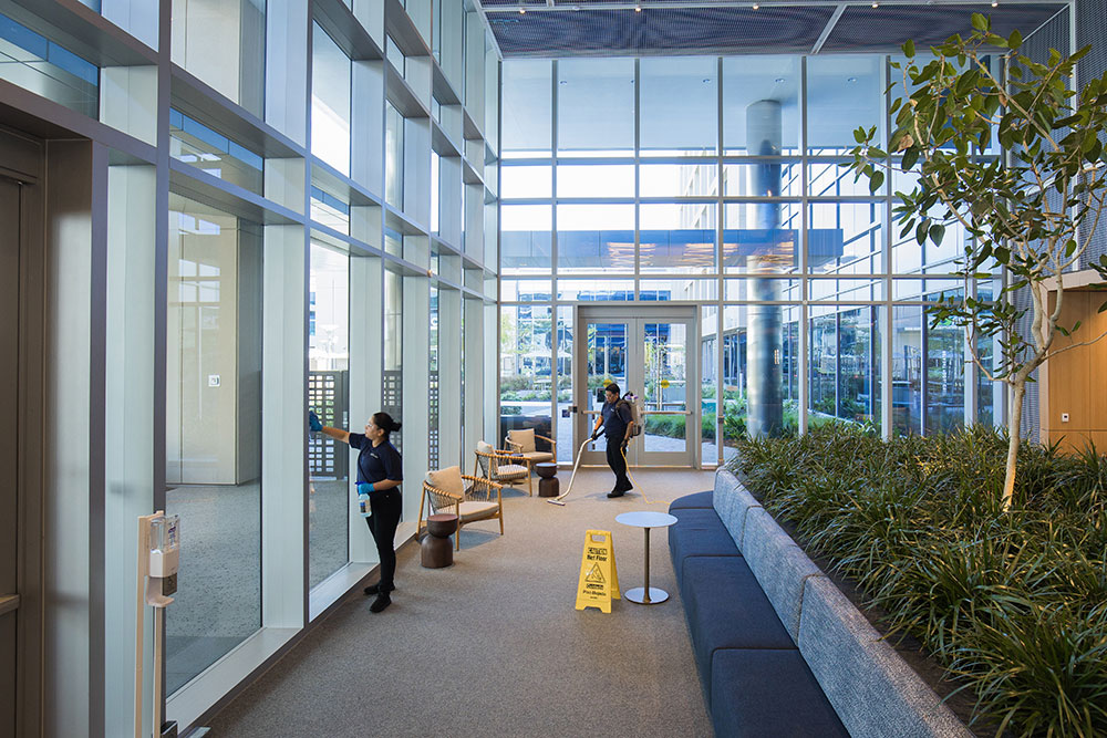 Commercial janitorial team cleaning the lobby of a corporate campus office building.