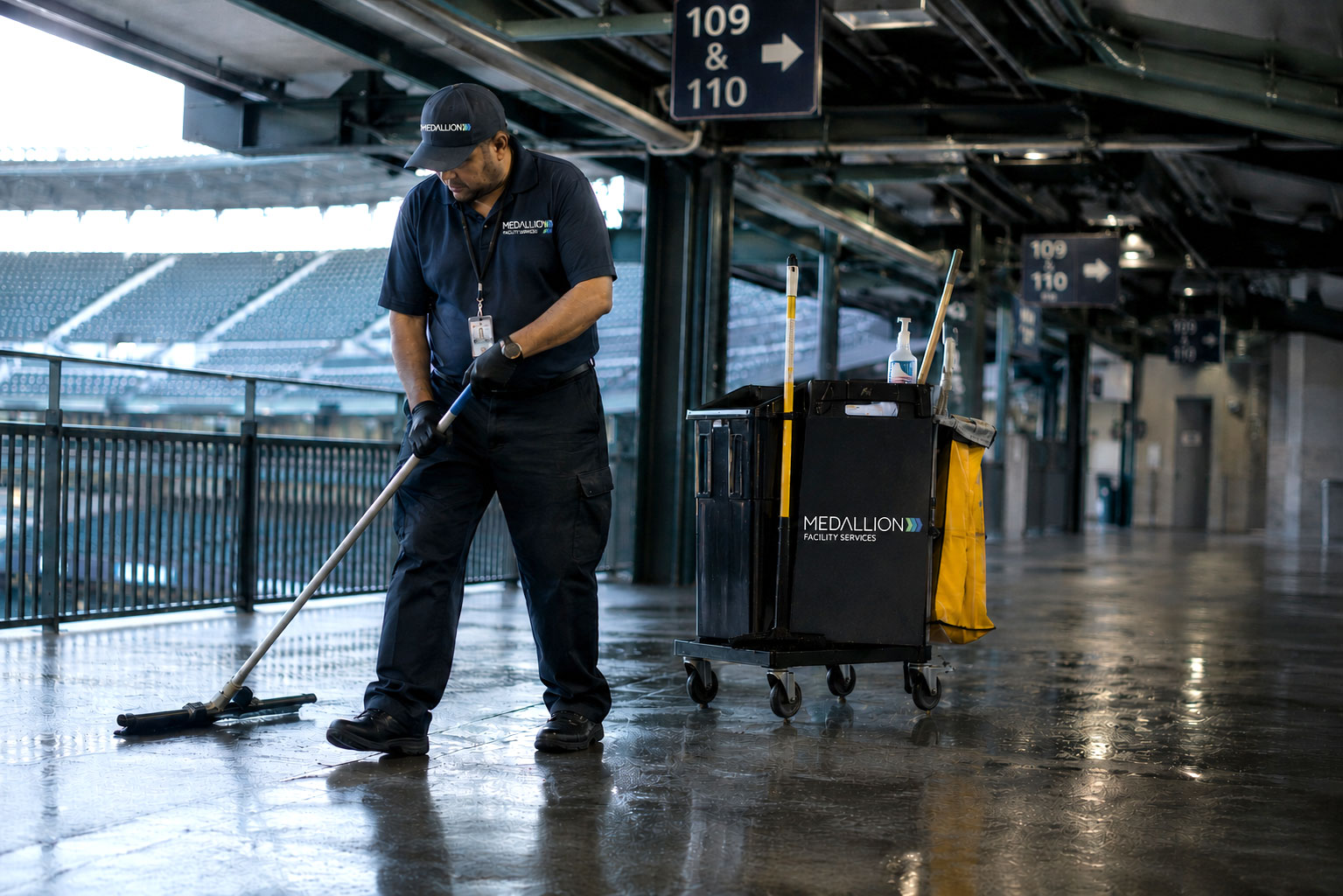 Janitorial professional providing event venue cleaning services in a stadium concourse